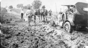 horse team pulling the car out of a muddy rut